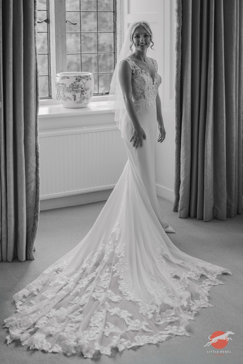 Black-and-white portrait of a bride showing the lace train of her wedding dress at Askham Hall