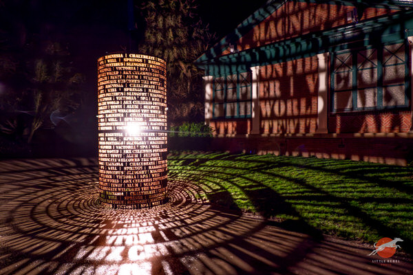 Illuminated 1571 sculpture casting patterned shadows beside Harrogate’s Royal Pump Room