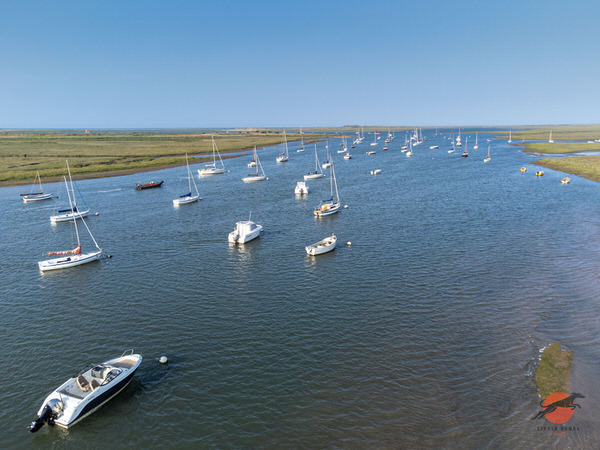 Aerial view of sailing boats moored in a tidal channel on the North Norfolk coast